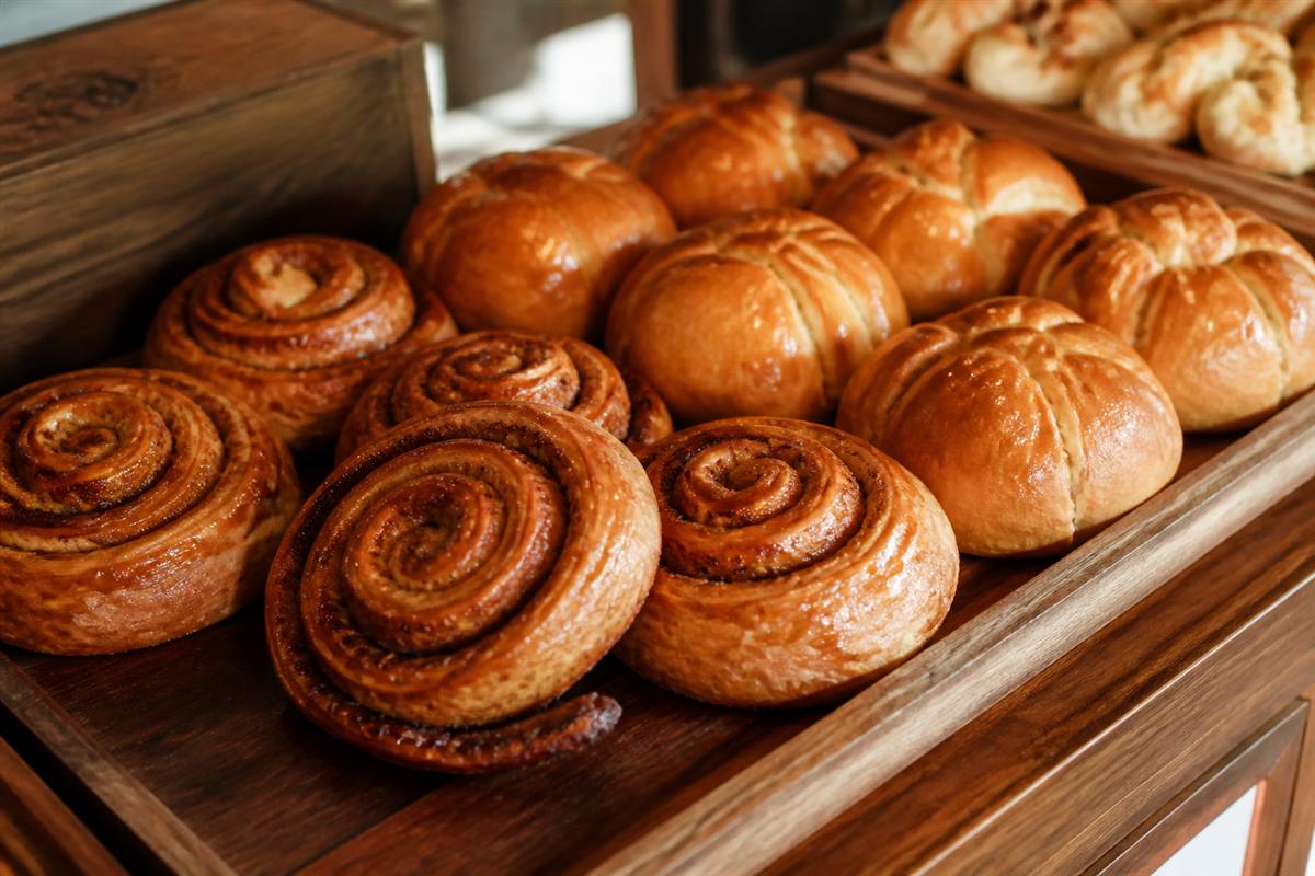 Glazed cinnamon rolls and golden bakery buns on wood trays